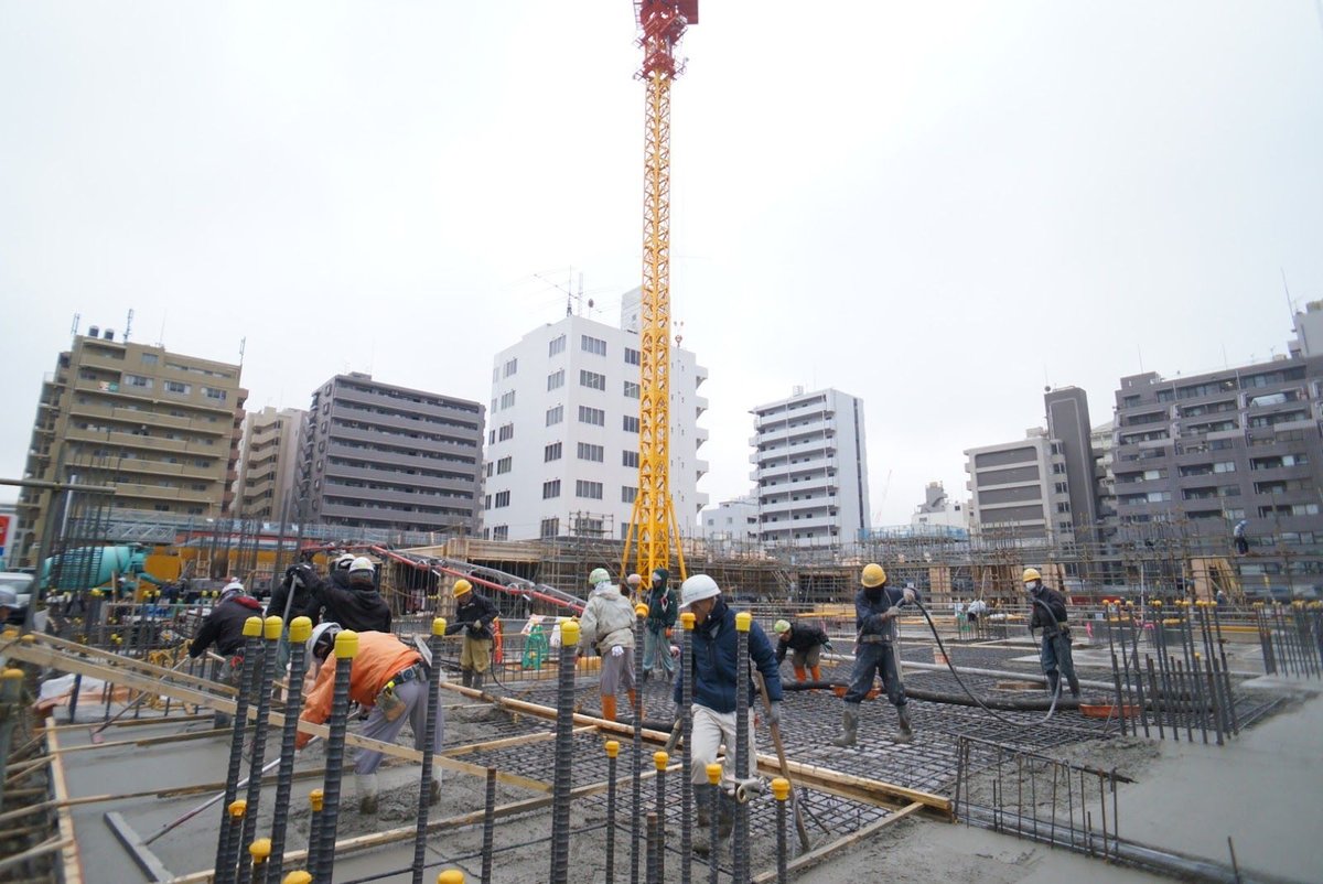 クレーンが立つ建築現場でのコンクリート打設の様子