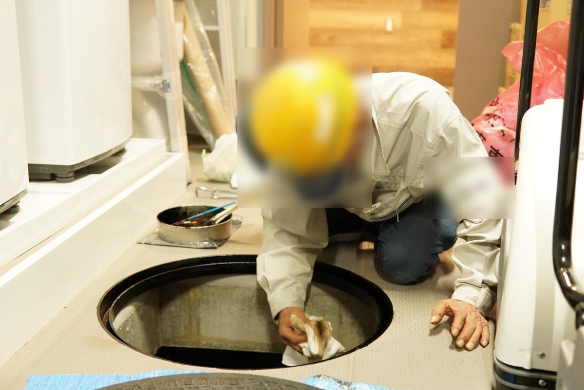 床下点検口から配管と設備を確認する作業員